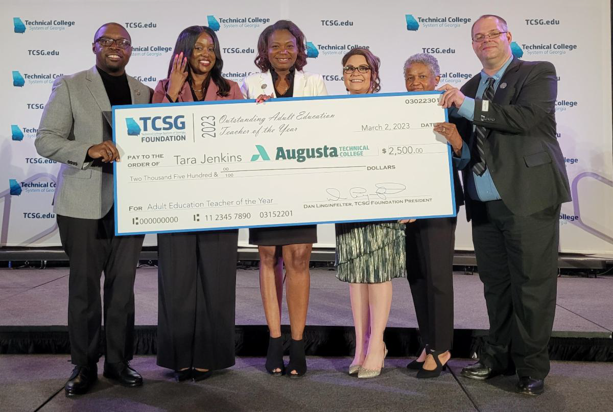Dr. Whirl, the president of Augusta Technical College, stands with the 2022 and 2023 Adult Education Teacher of the Year winners as well as the 2022 EAGLE winner and Dean Moseley while holding the check from TCSG.