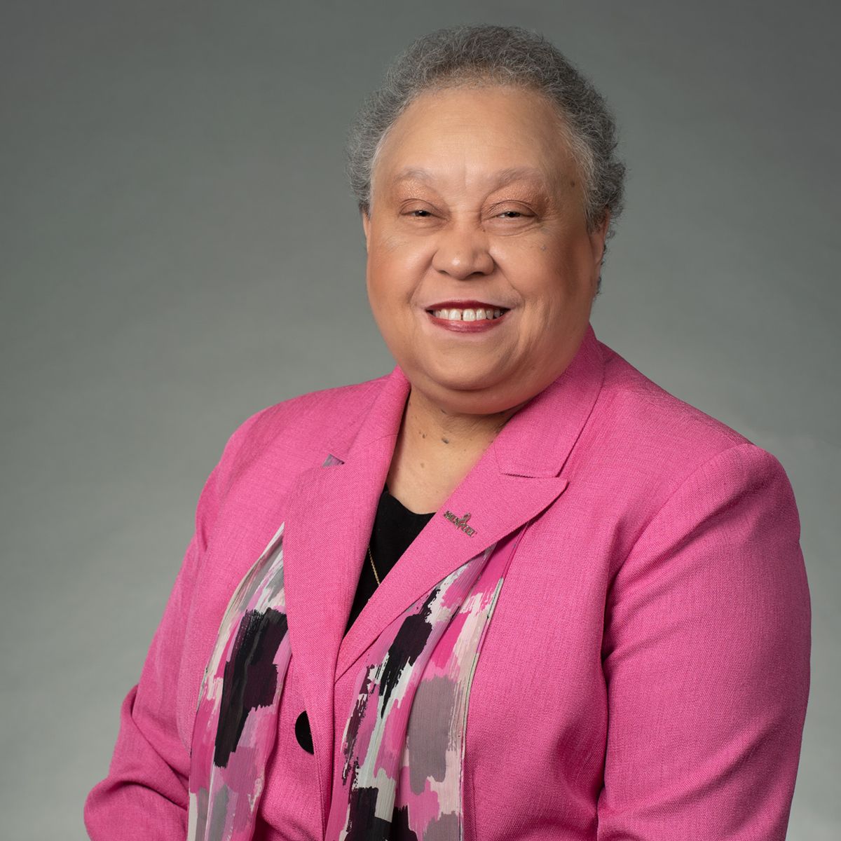 Dr. Belle Wheelan, am African American female wearing a pink blazer with a black, white, pink and gray color splats, and a black blouse. 